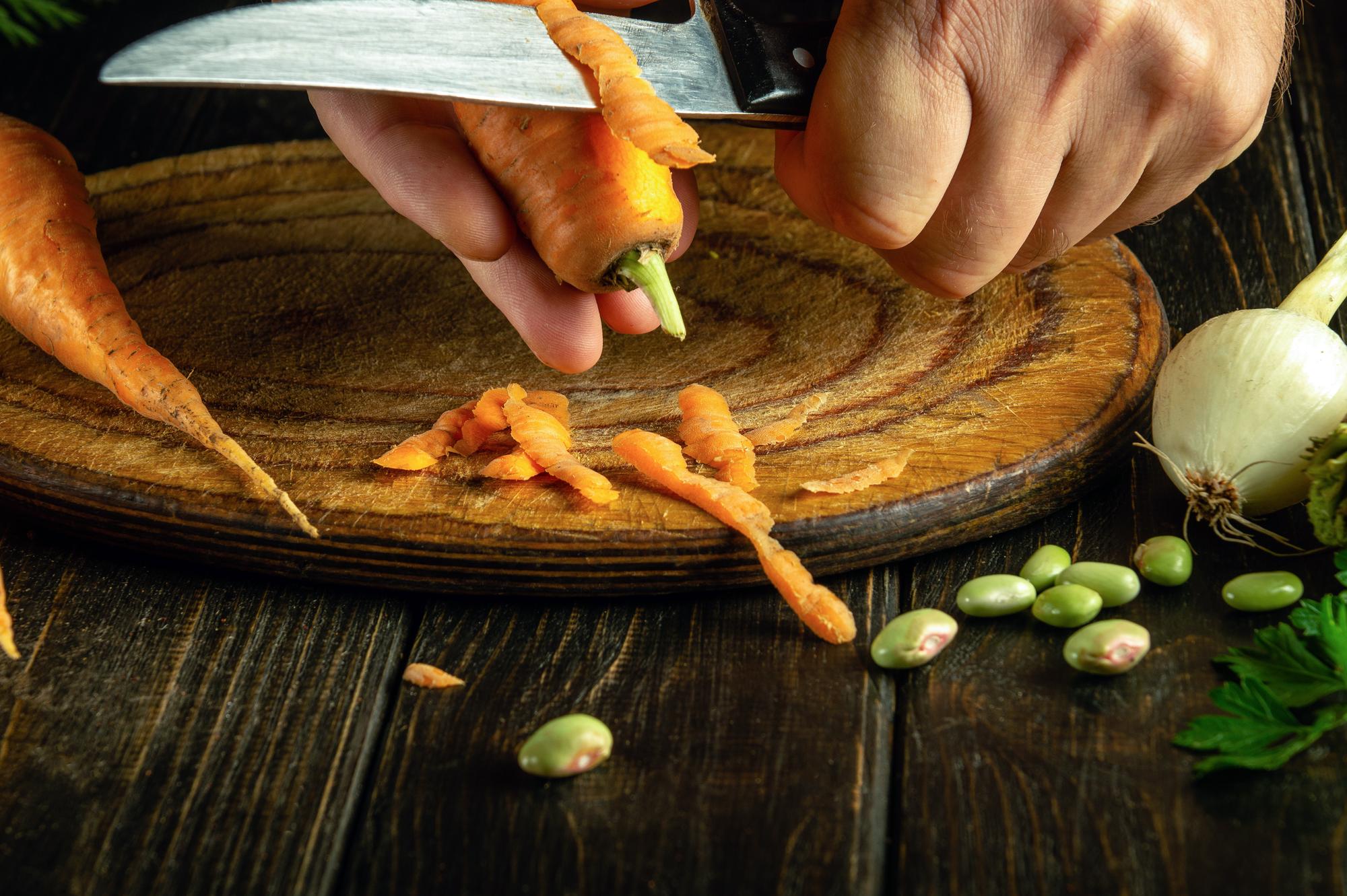 Hands sprinkling herbs over roasted carrots